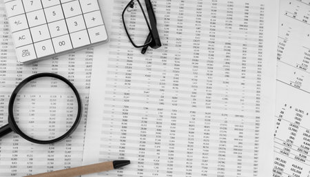 Calculator, magnifying glass, pen, eye glasses on financial documents.の写真素材