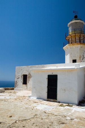 An old white lighthouse with a blue ocean in the background. の写真素材