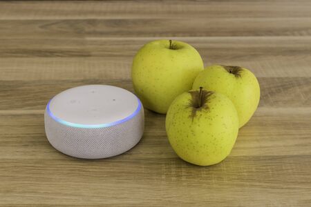 Voice controlled speaker with activated voice recognition for weather, on wood background with apple