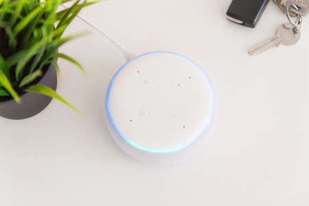 Voice controlled speaker with activated voice recognition with car key white background.