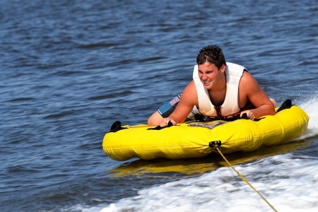 Teenage sliding across boat wake in inner tube scouting out the next jump  Getting ready to cross wake for his next jumpの写真素材