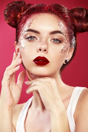 Bright beautiful readhead girl with tinsel and buns hairstyle. Art makup.. Ads for hairdressers and beauty salon.の写真素材