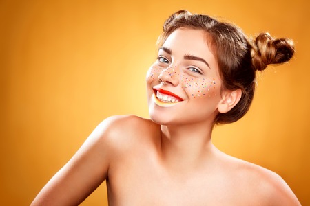 Youth women with glitter freckles on face, yellow background. Perfect skin. Art conceptの写真素材