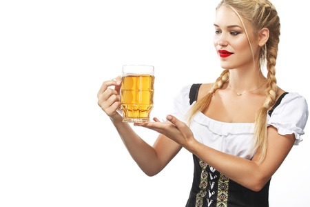Half-length portrait of young sexy blonde with big breast wearing black dirndl with white blouse holding the beer mug Isolated on dark backgroundの写真素材