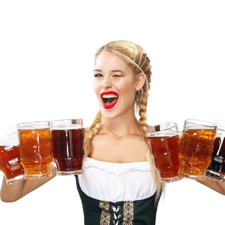 Half-length portrait of young sexy blonde with big breast wearing black dirndl with white blouse holding the beer mug Isolated on dark backgroundの写真素材