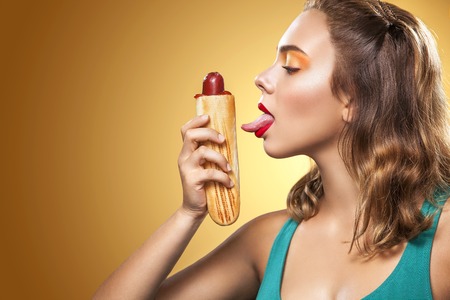 Young sexy woman eating big french hot-dog on Oktoberfest holidayの写真素材