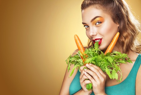 Young sexy woman eating having fun eating vegetarian food - carrotの写真素材