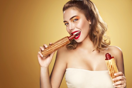 Young sexy woman eating big french hot-dog on Oktoberfest holidayの写真素材