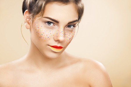 Youth women with glitter freckles on face, yellow background. Perfect skin. Art conceptの写真素材