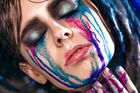 Portrait of a woman with painted face. Creative makeup and bright style.の写真素材