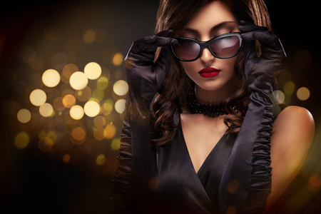 Vogue style close-up portrait of beautiful woman. Long curly brunette hair on black background with lights. St valentines dayの写真素材
