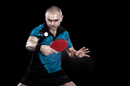 Young sports man tennis-player in play on black background. Action shot.の写真素材
