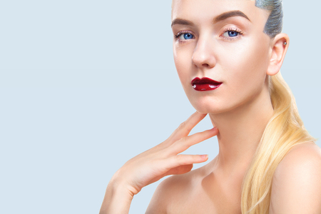 Close-up portrait of sexy blonde girl with makeup. Beautiful model, silver hairstyle. isolated on blue background. For cosmetics ads. Copy Space.の写真素材