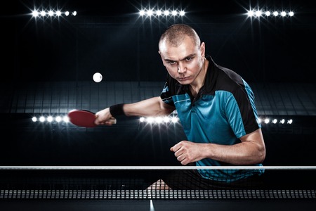 Portrait of sports man, male, athlete playing table tennis isolated on black backgroundの写真素材