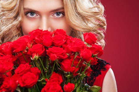 Beautiful blonde woman holding bouquet of red roses. Saint Valentine and International Womens Day, Eight March celebration.の写真素材