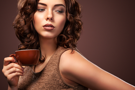beautiful young woman with a cup of coffee on the dark backgroundの写真素材