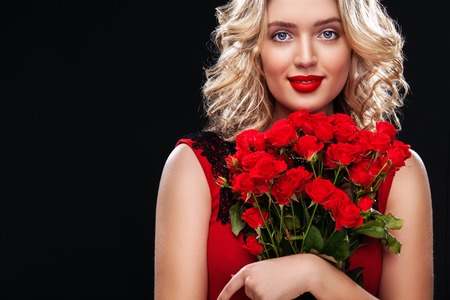 A portrait of a young beautiful blonde woman with red flowers. Saint Valentine and International Women's Day, Eight March celebration.の写真素材
