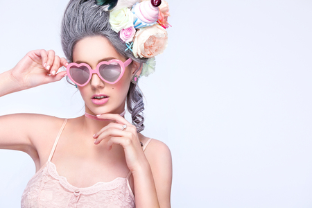 Beautiful blonde woman with a cake. Sweet sexy lady with heart glasses. Vintage style. Fashion photoの写真素材