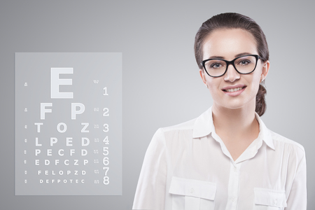 Woman wearing glasses with Snellen test chart on background.の写真素材