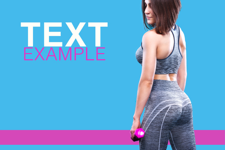 Sport fitness woman doing exercise with red dumbbells near a blue wall. Copy space for advertisement poster.の写真素材