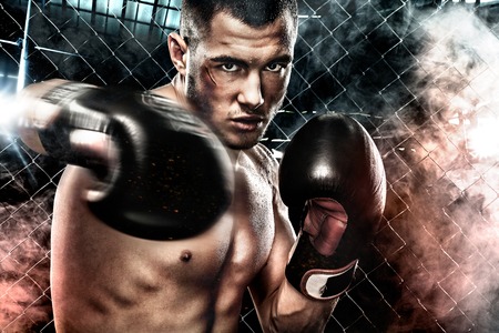 Sportsman muay thai boxer fighting in boxing cage. Background with lights and smoke. Copy Space. Sport concept.の写真素材