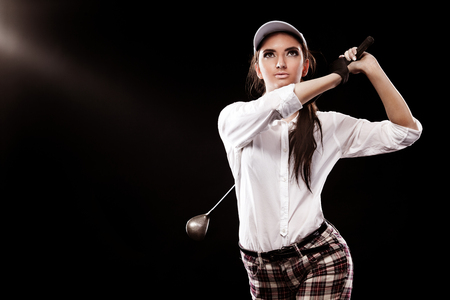 Woman golfer hitting the ball isolated on black background. Copy space. Ad concept.の写真素材