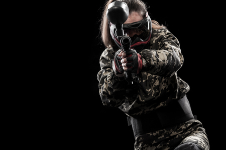 Heavily armed masked paintball soldier isolated on black background. Ad concept.の写真素材