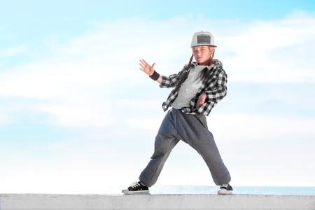 Happy little girl dancing hip-hop on blue sky backgroundの写真素材