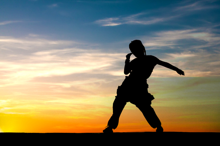 Silhouette of happy little girl dancing on sunset sky background. Copy space.の写真素材