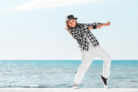 Happy little girl dance on sky background. Fashion kid. Copy space.の写真素材