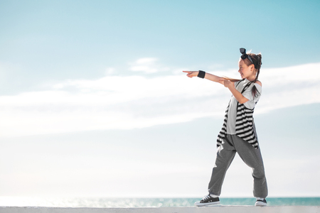 Girl child pointing on copy space over sky background. Fashion kid.の写真素材