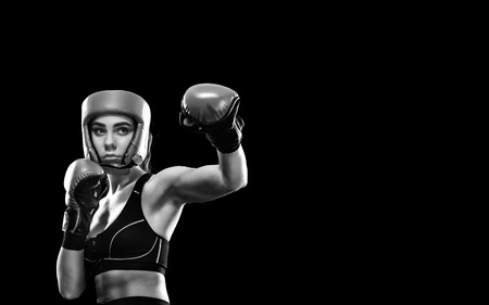 Woman boxer fighting in boxing cage. Isolated on black background. Copy Space. Black and white photo.の写真素材