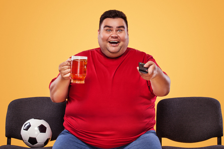 Half-length portrait of young fat man with holding the beer mug Isolated on solid backgroundの写真素材