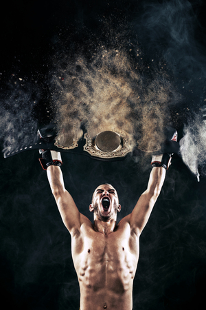 Boxer with Champion belt celebrating flawless victory isolated on black background with copy Space..の写真素材