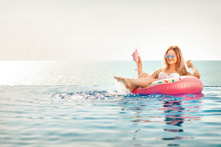 Summer Vacation. Woman in bikini on the inflatable donut mattress in the SPA swimming pool.の写真素材