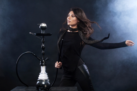 Young, beautiful woman in the night club or bar smoke a hookah or shisha. The pleasure of smoking. Sexy smoke.の写真素材