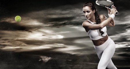Beautiful sport woman tennis player with racket in white sportswear costumeの写真素材