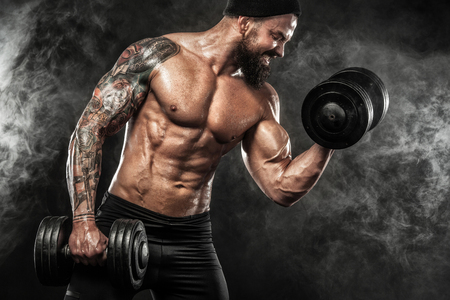 Muscular young fitness sports man workout with dumbbell in fitness gymの写真素材