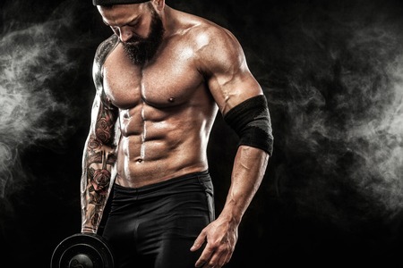 Muscular young fitness sports man workout with dumbbell in fitness gymの写真素材