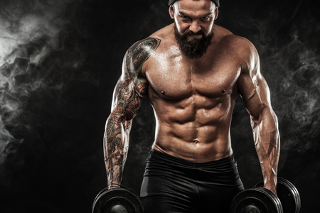 Muscular young fitness sports man workout with dumbbell in fitness gymの写真素材