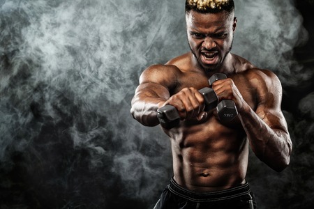 Muscular young fitness sports man workout with dumbbell in fitness gymの写真素材
