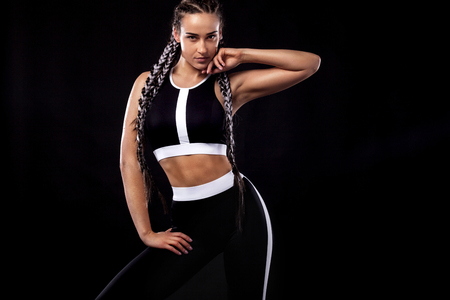 A strong athletic woman on black background wearing in black sportswear, fitness and sport motivation. Sport concept with copy space.の写真素材