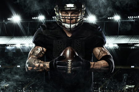 Sport concept. American football sportsman player holding ball on stadium.の写真素材