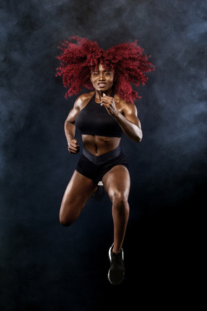 A strong athletic, female sprinter, running at sunrise wearing in the sportswear, fitness and sport motivation concept with copy space.の写真素材