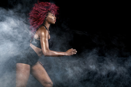 A strong athletic, female sprinter, running at sunrise wearing in the sportswear, fitness and sport motivation concept with copy space.の写真素材
