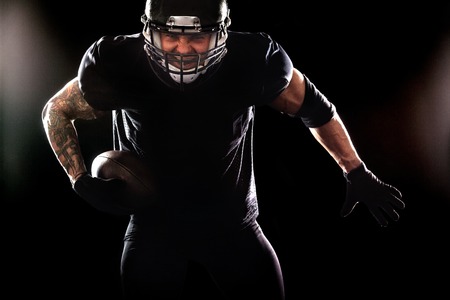 American football sportsman player isolated on black backgroundの写真素材