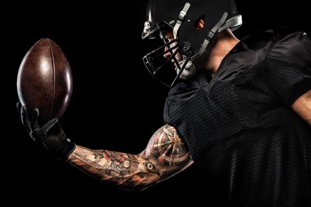 American football sportsman player isolated on black backgroundの写真素材