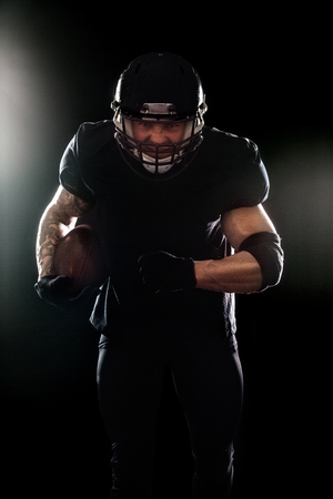 American football sportsman player isolated on black backgroundの写真素材