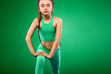 Kid girl doing fitness exercises on green backgroundの写真素材
