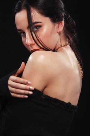 Portrait of beautiful sexy brunnete girl, on black background. Pretty girl model. A brunette woman in a black dress.の写真素材